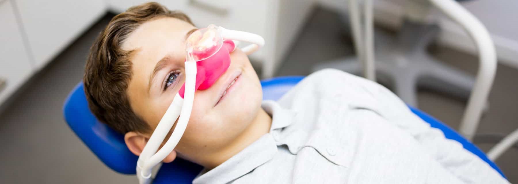 A young boy sitting in a dentist chair, receiving sedation dentistry at Washington